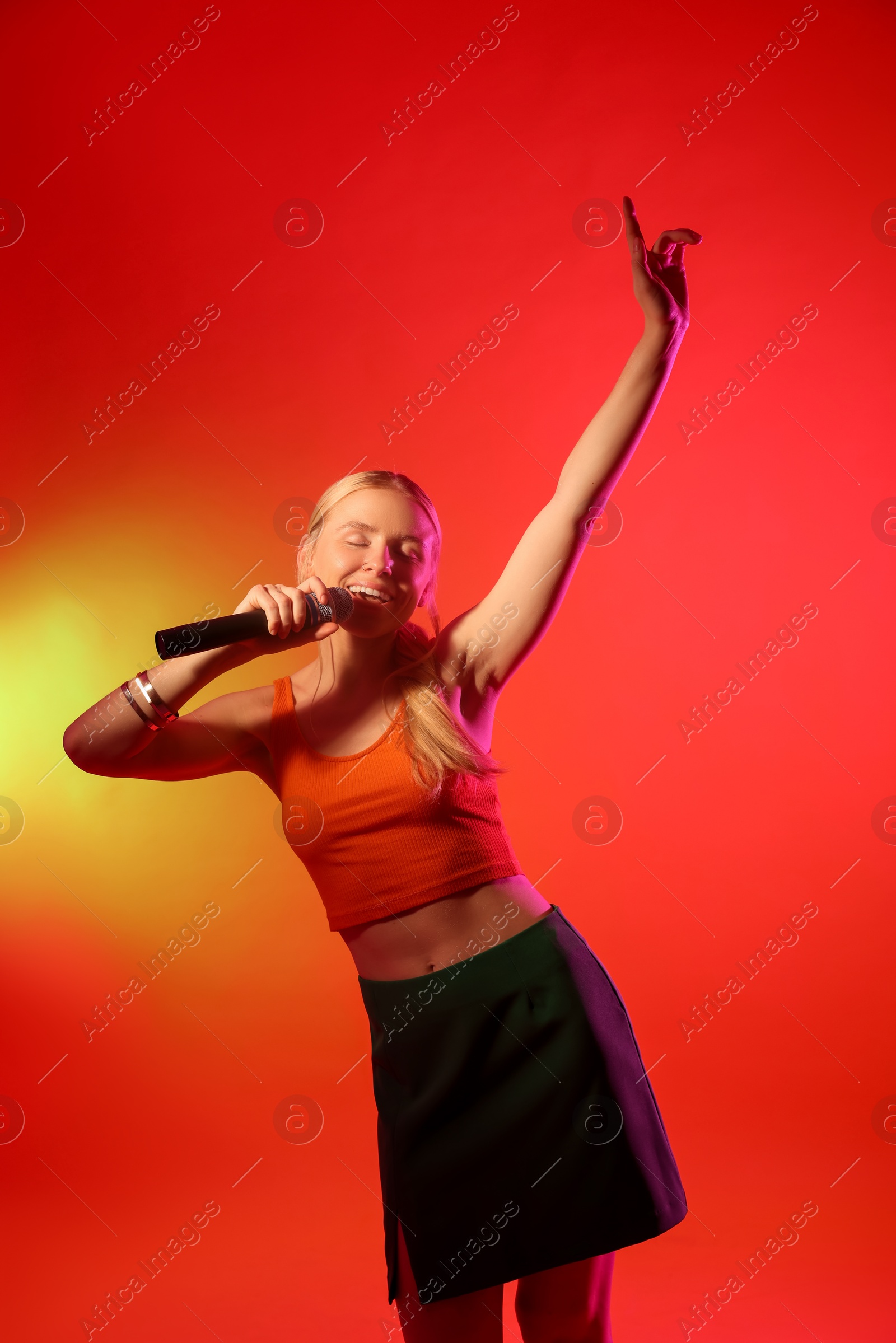 Photo of Talented singer performing on red background with yellow light