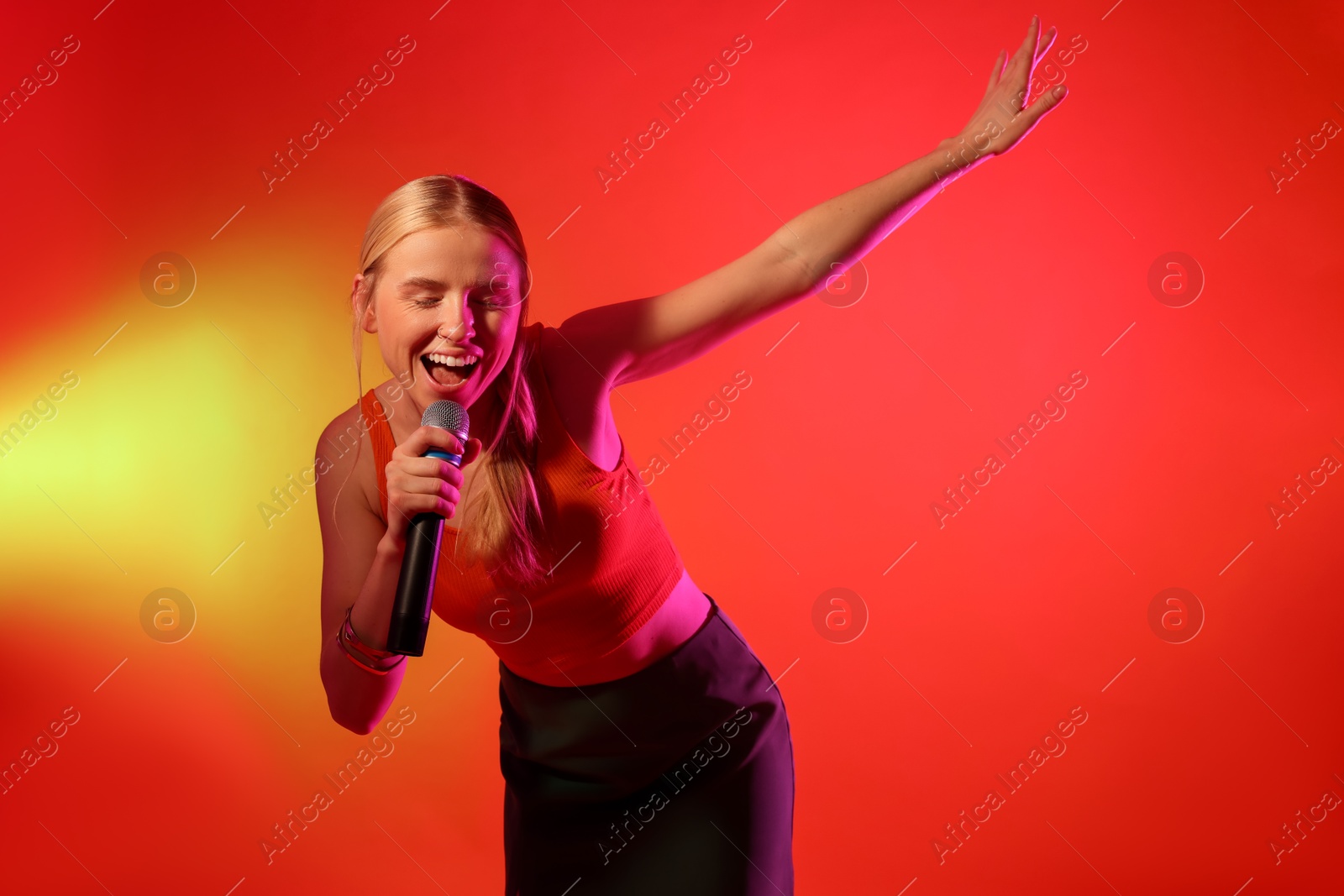 Photo of Talented singer performing on red background with yellow light