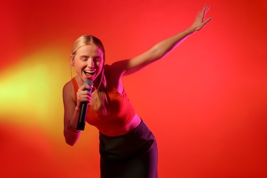 Photo of Talented singer performing on red background with yellow light