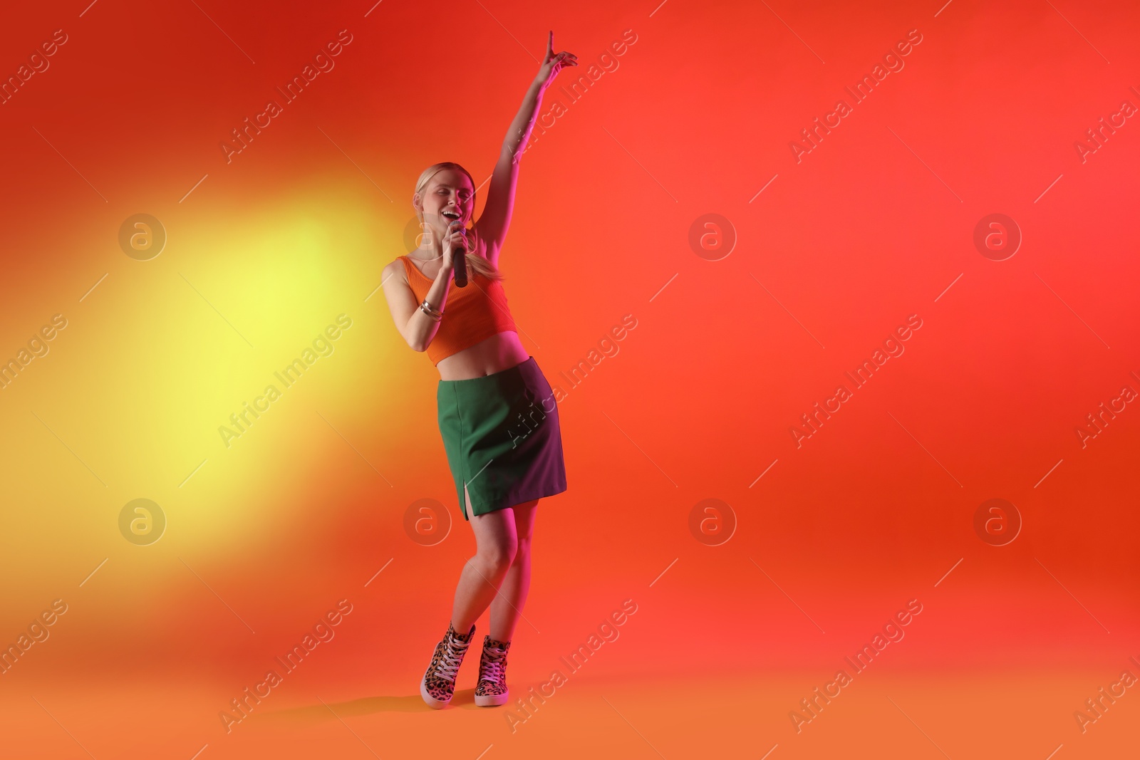 Photo of Talented singer performing on red background with yellow light