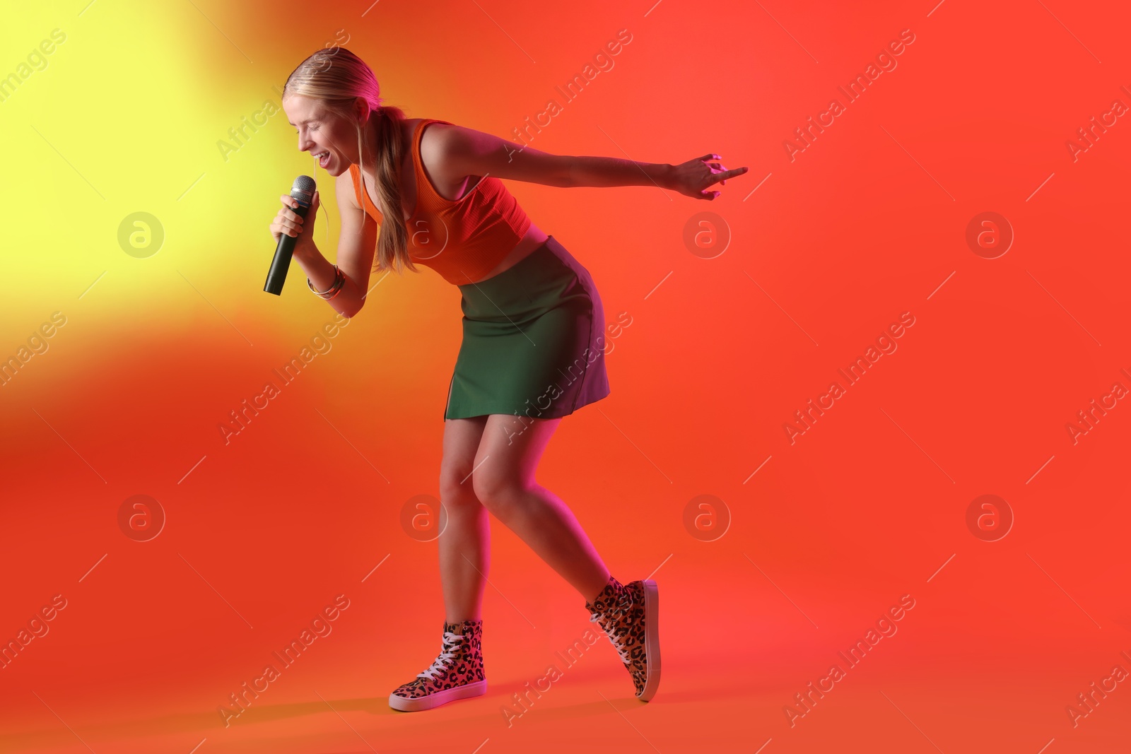 Photo of Talented singer performing on red background with yellow light. Space for text