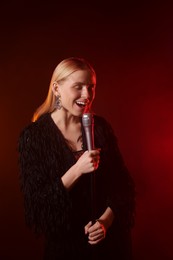 Beautiful singer performing on dark background with red light