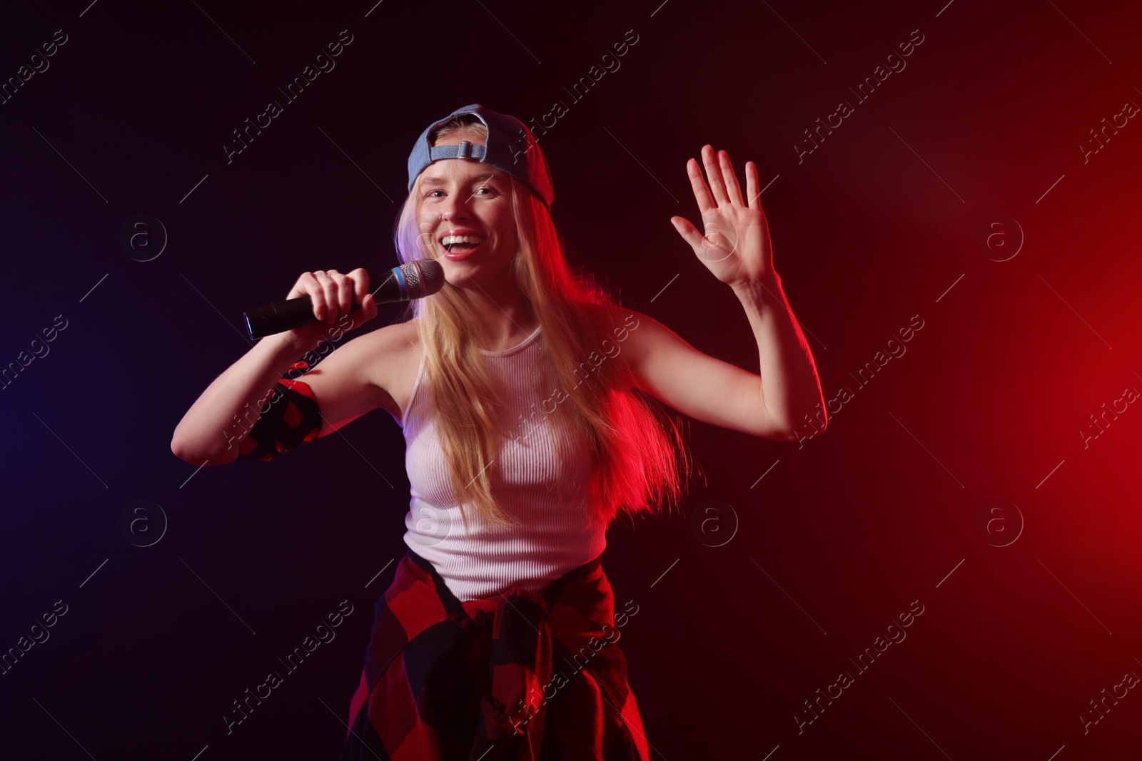 Photo of Talented singer performing on dark background with color lights