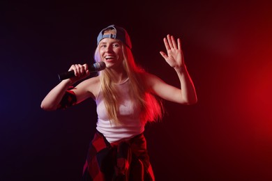 Talented singer performing on dark background with color lights