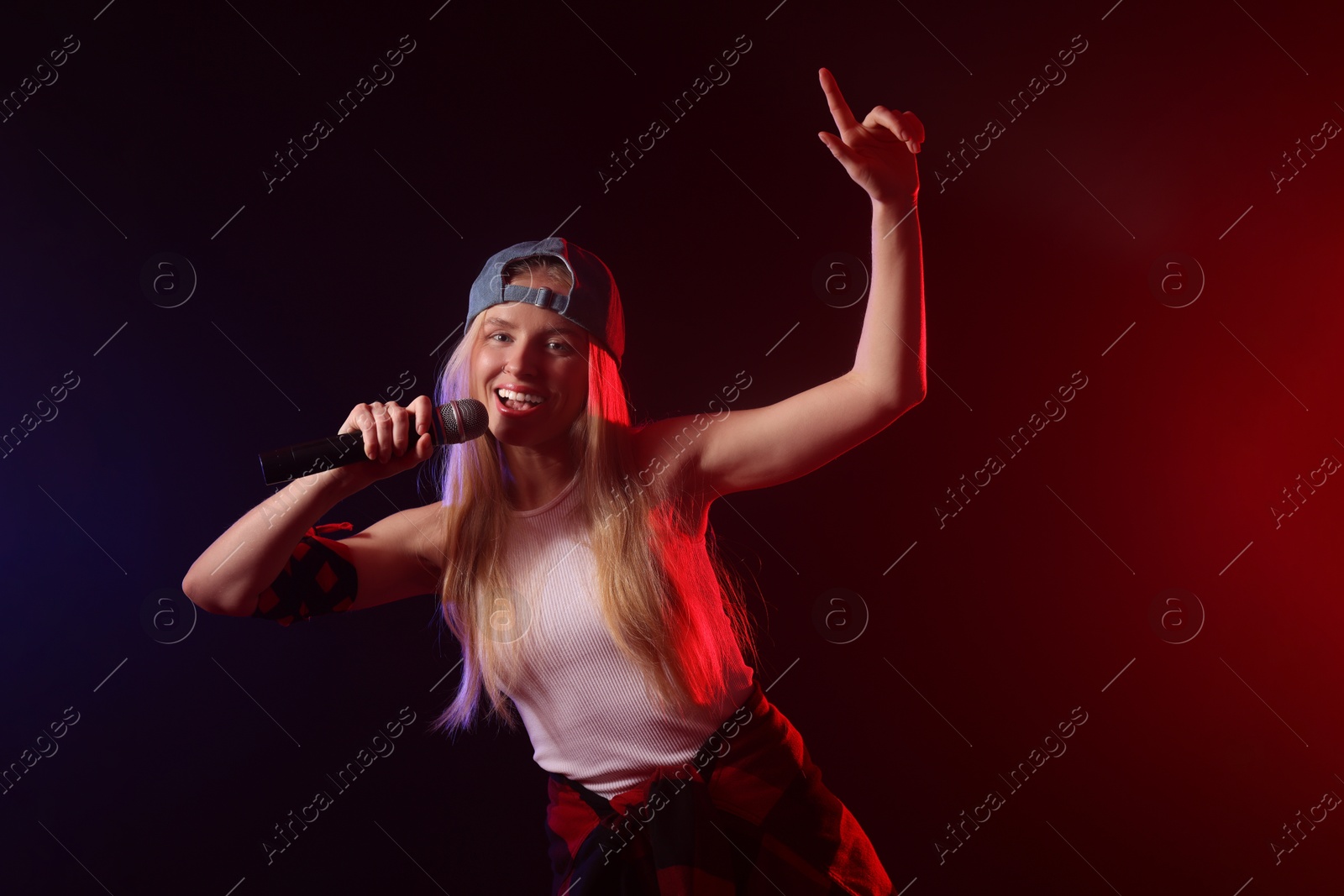 Photo of Talented singer performing on dark background with color lights