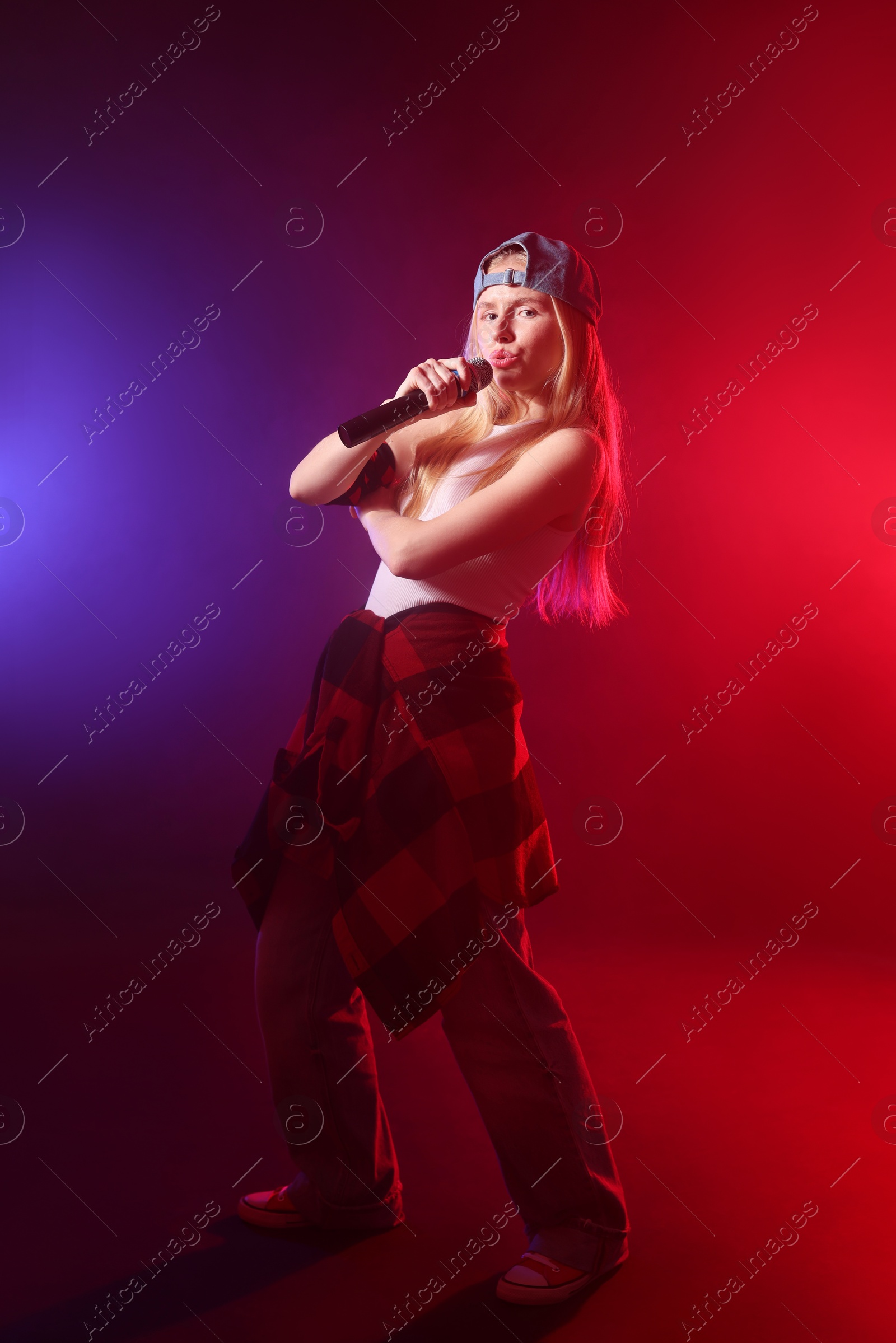 Photo of Talented singer performing on dark background with color lights