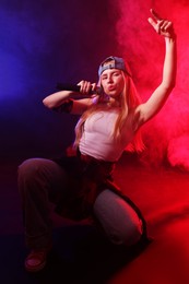 Photo of Talented singer performing on dark background with color lights and smoke