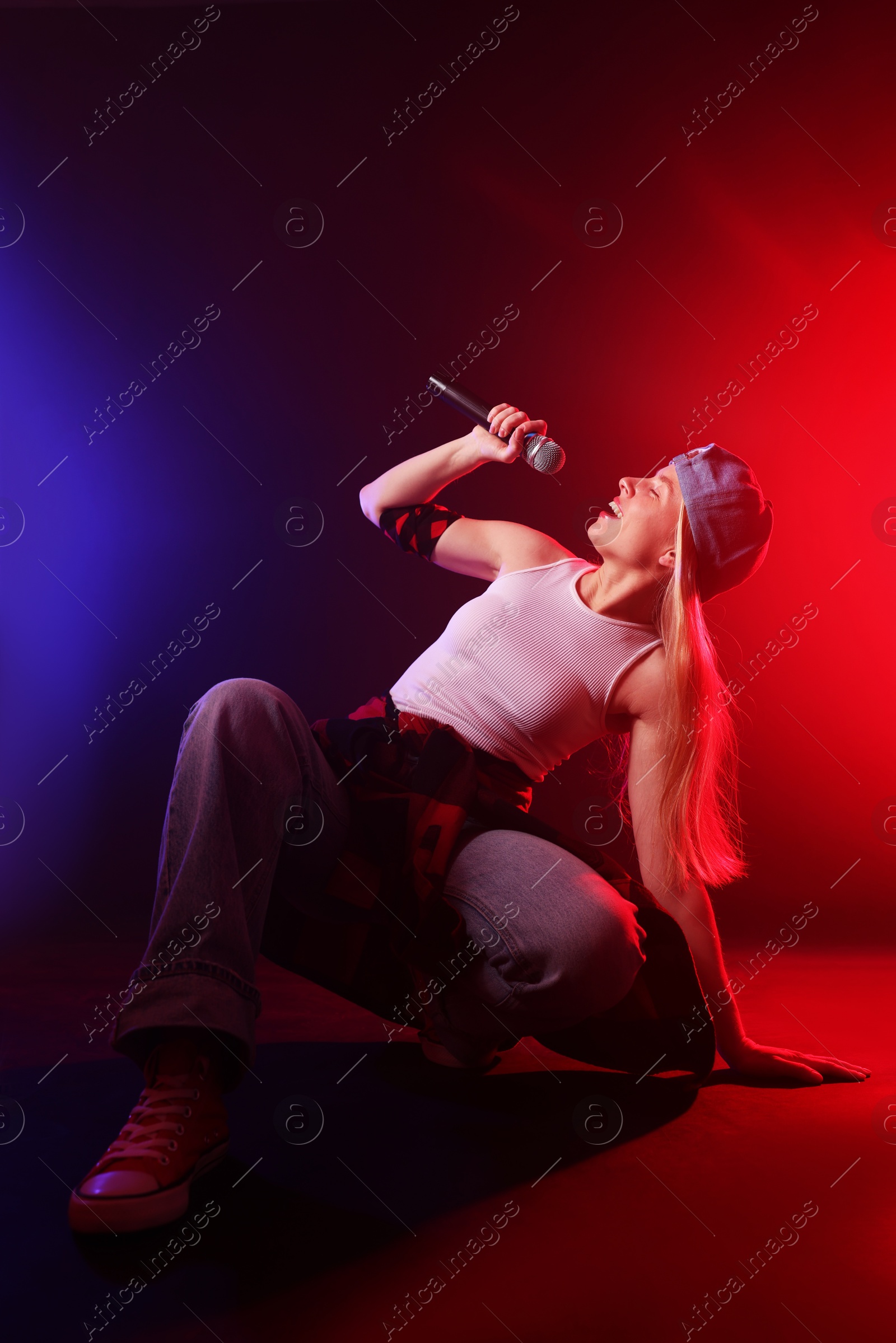 Photo of Talented singer performing on dark background with color lights