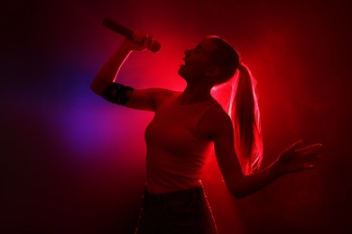 Photo of Beautiful talented woman singing in red light