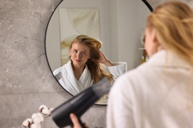 Photo of Beautiful young woman drying her hair in bathroom