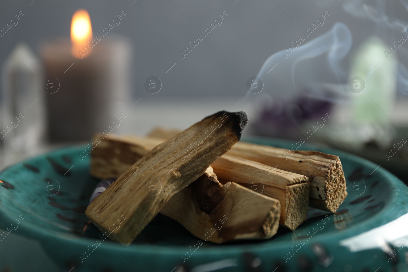 Photo of Smoldering palo santo stick on table, closeup