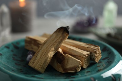 Photo of Smoldering palo santo stick on table, closeup