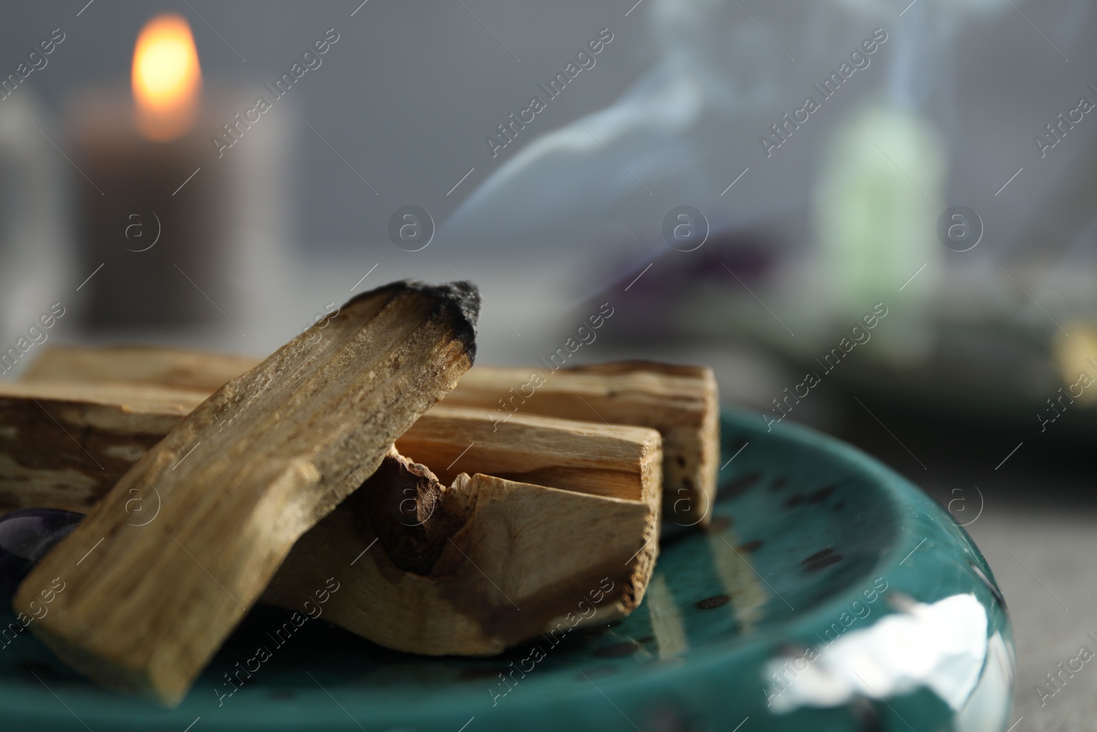 Photo of Smoldering palo santo stick on table, closeup