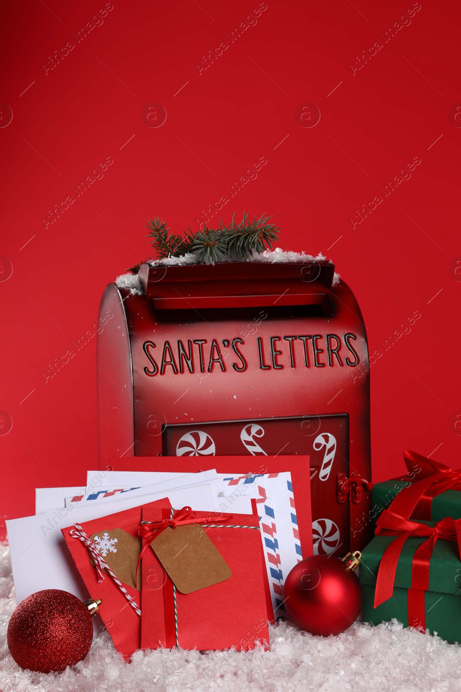 Photo of Santa Claus mailbox with letters, Christmas gifts, baubles on artificial snow against red background