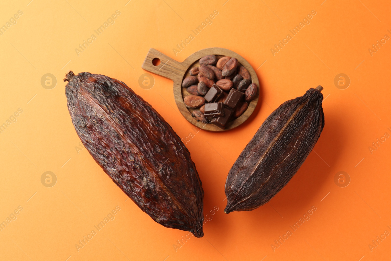 Photo of Cocoa pods and beans on orange background, top view