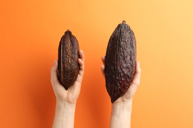 Photo of Woman with cocoa pods on orange background, closeup