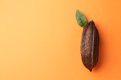 Natural cocoa pod on orange background, top view. Space for text