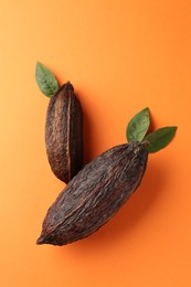 Photo of Natural cocoa pods on orange background, top view