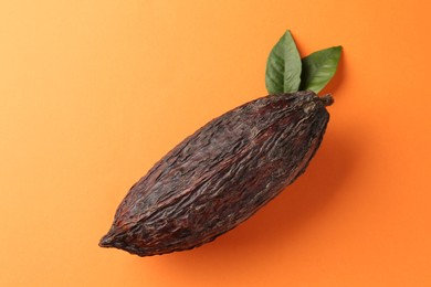 Photo of Natural cocoa pod on orange background, top view