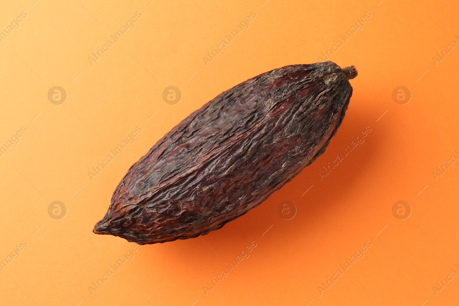 Photo of Natural cocoa pod on orange background, top view