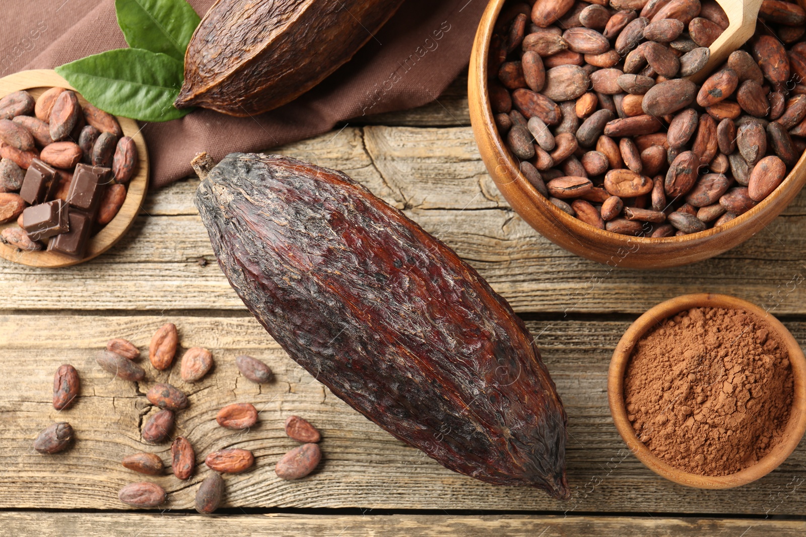 Photo of Cocoa pod, powder and beans on wooden table, flat lay