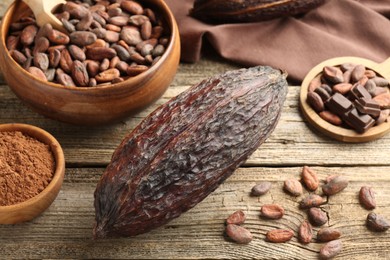 Photo of Cocoa pod, powder and beans on wooden table, closeup