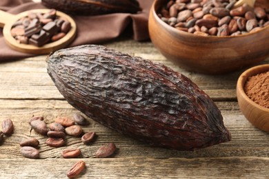 Photo of Cocoa pod, powder and beans on wooden table, closeup