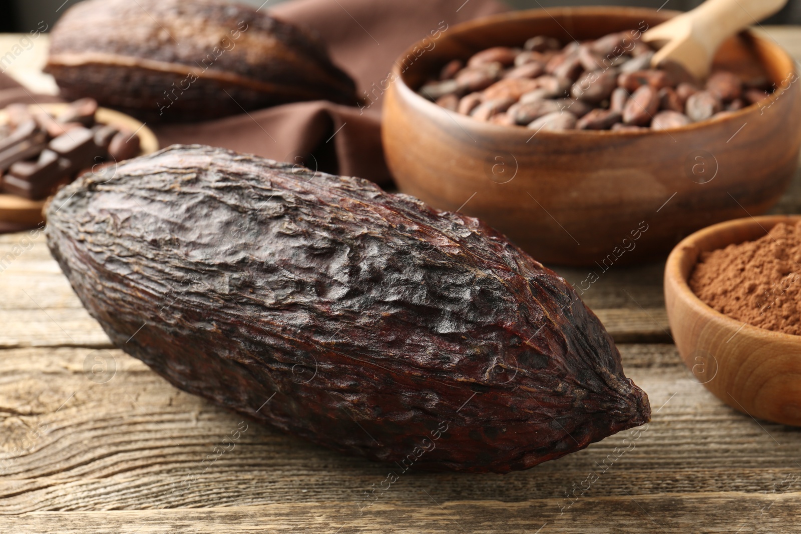 Photo of Cocoa pods, powder and beans on wooden table, closeup