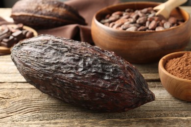 Photo of Cocoa pods, powder and beans on wooden table, closeup