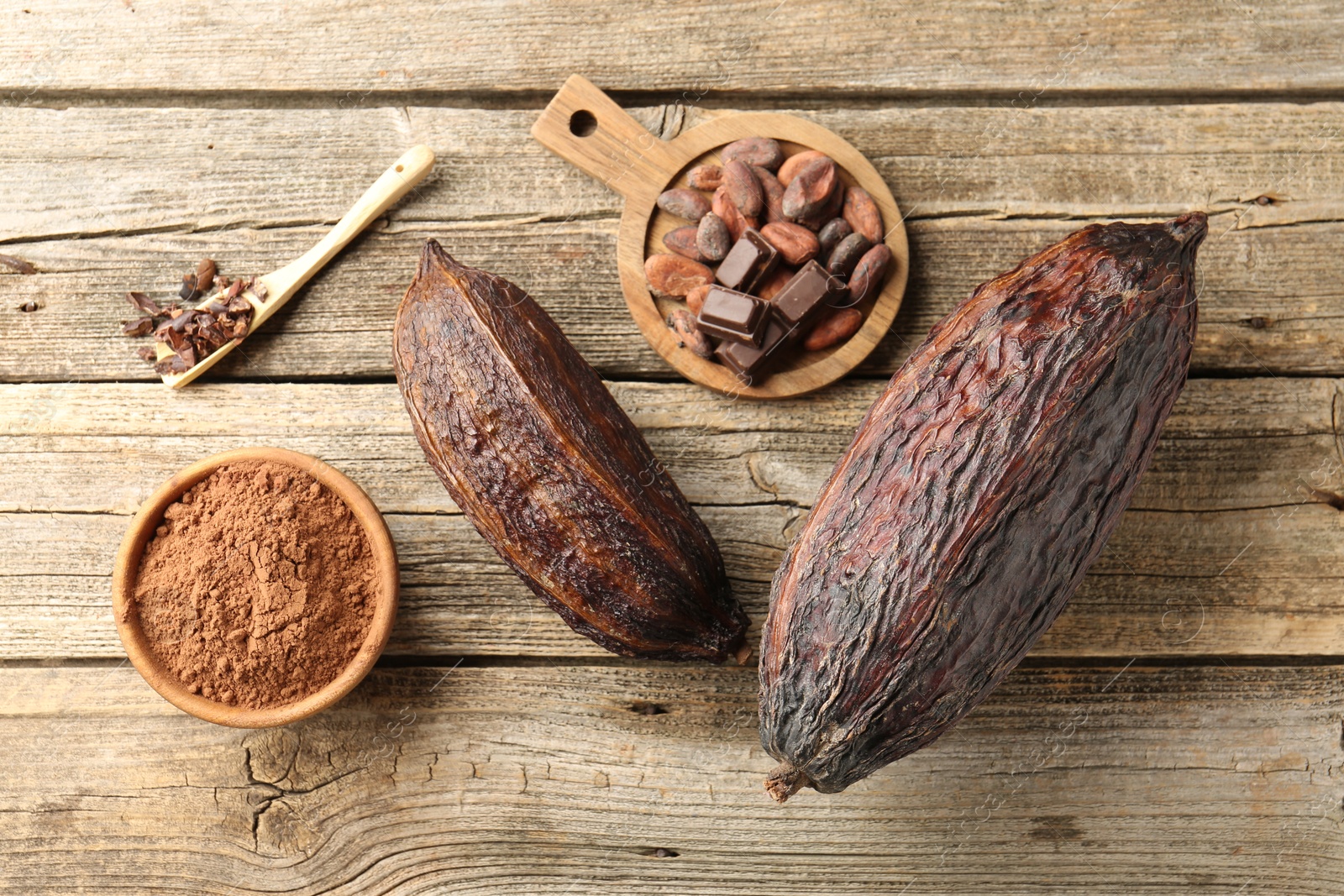 Photo of Cocoa pods, powder and beans on wooden table, flat lay