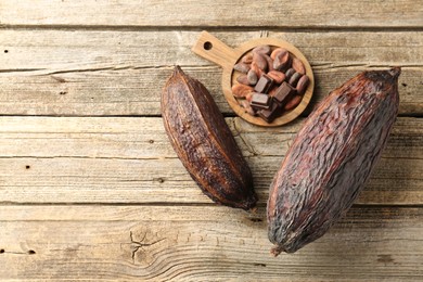 Photo of Cocoa pods and beans on wooden table, top view. Space for text