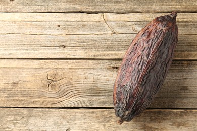 Photo of Cocoa pod on wooden table, top view. Space for text