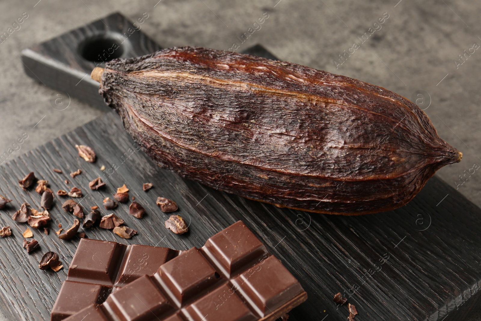 Photo of Cocoa pod and chocolate on grey table, closeup