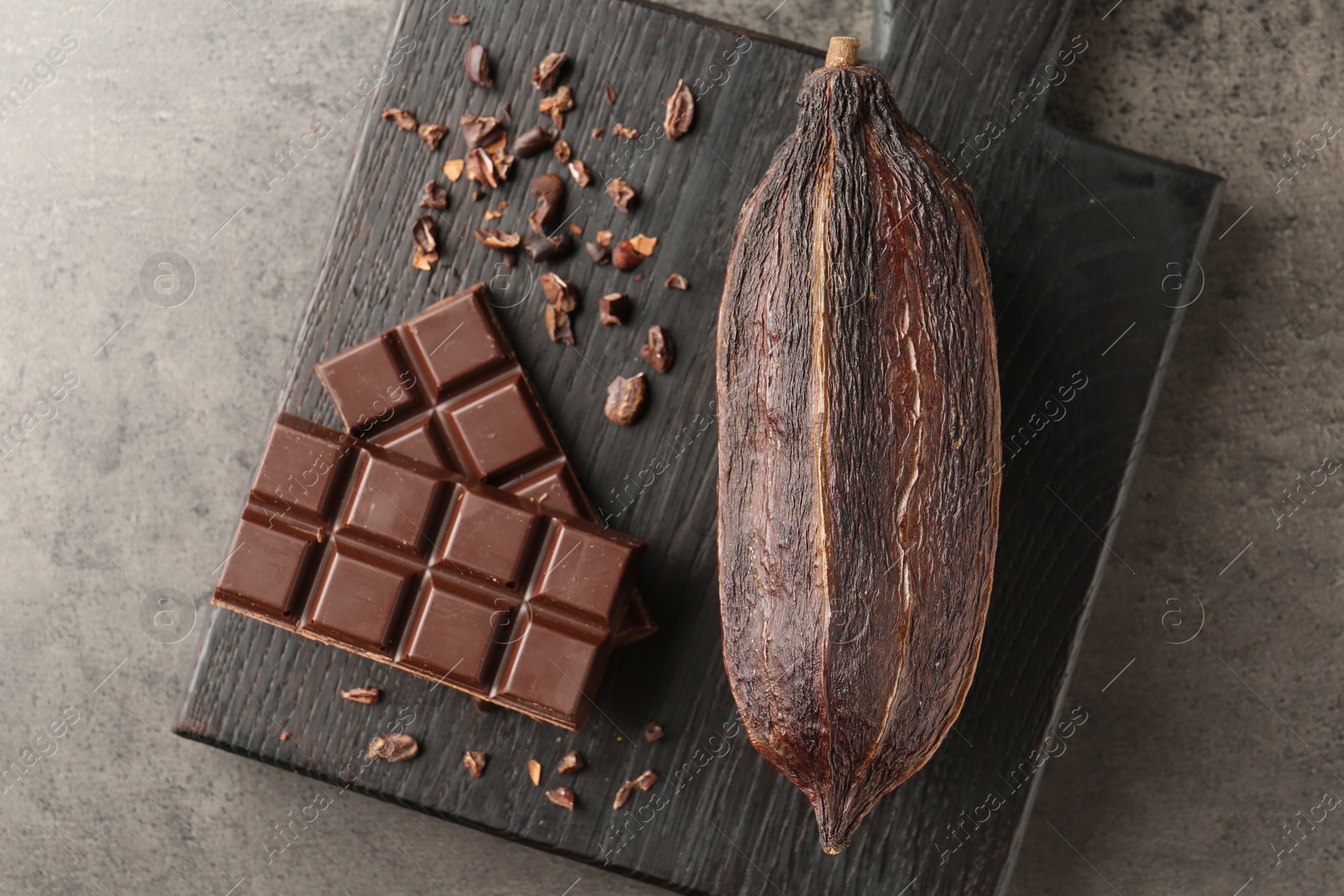 Photo of Cocoa pod and chocolate on grey table, top view