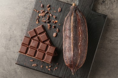 Photo of Cocoa pod and chocolate on grey table, top view