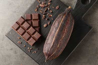 Photo of Cocoa pod and chocolate on grey table, top view