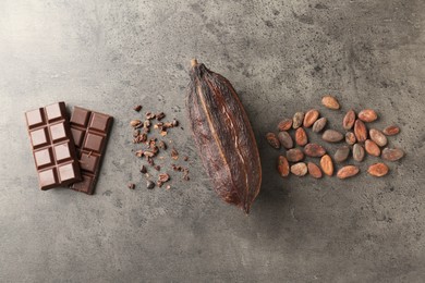 Cocoa pod, beans and chocolate on grey table, flat lay