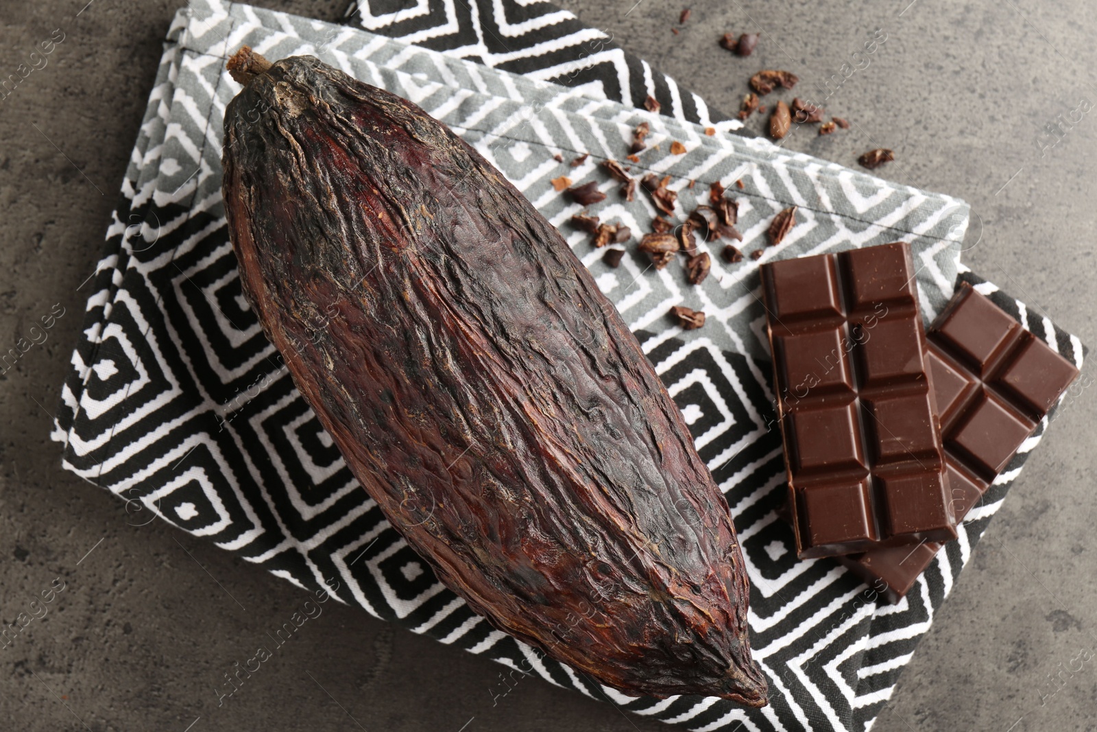 Photo of Cocoa pod and chocolate on grey table, top view