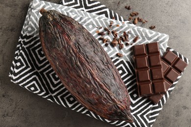 Photo of Cocoa pod and chocolate on grey table, top view