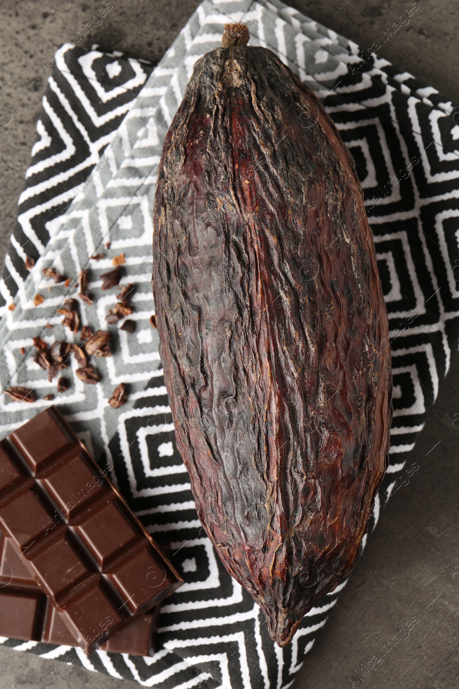 Photo of Cocoa pod and chocolate on grey table, top view