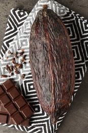 Cocoa pod and chocolate on grey table, top view