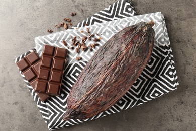 Photo of Cocoa pod and chocolate on grey table, top view