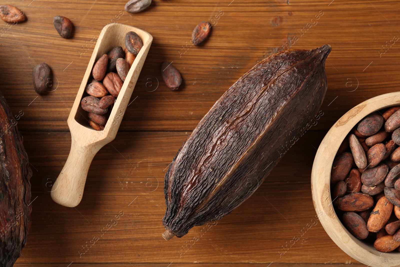 Photo of Cocoa pod and beans on wooden table, flat lay