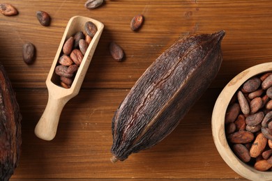 Photo of Cocoa pod and beans on wooden table, flat lay