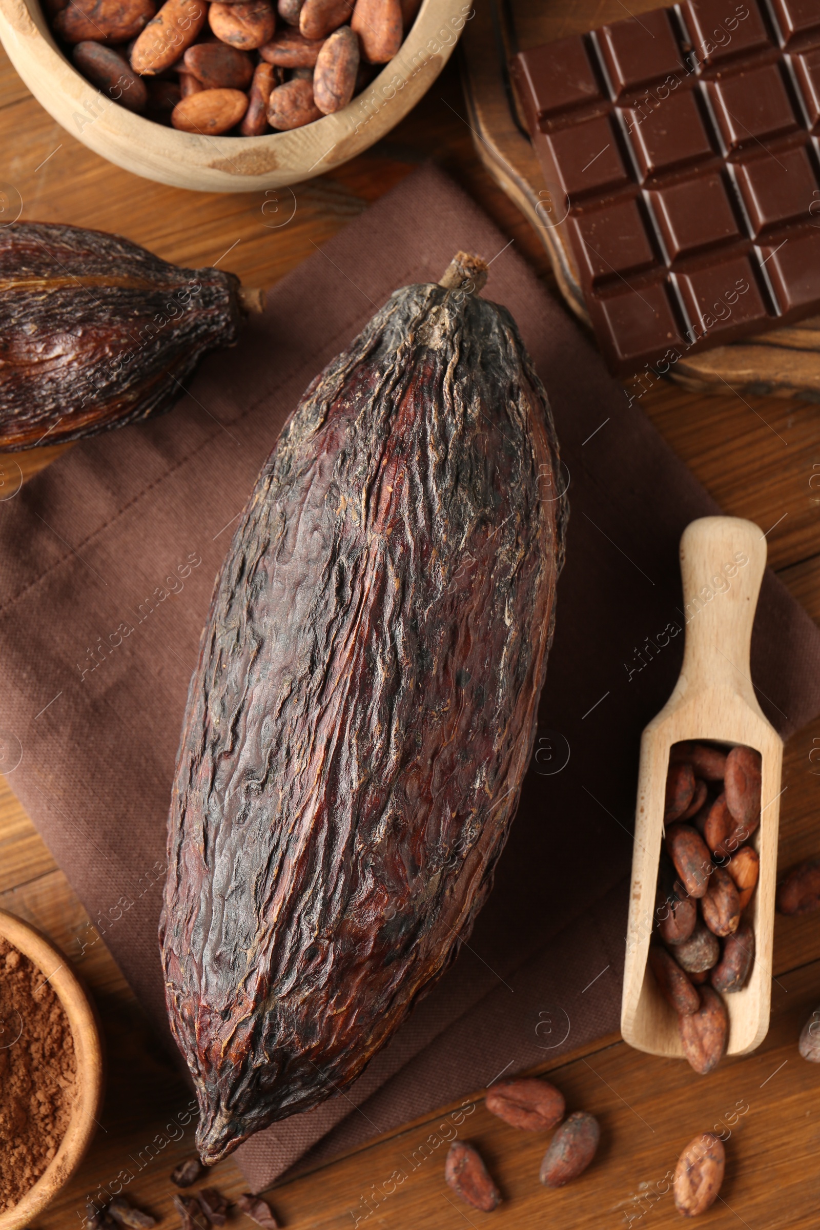 Photo of Cocoa pod, beans, powder and chocolate on wooden table, closeup