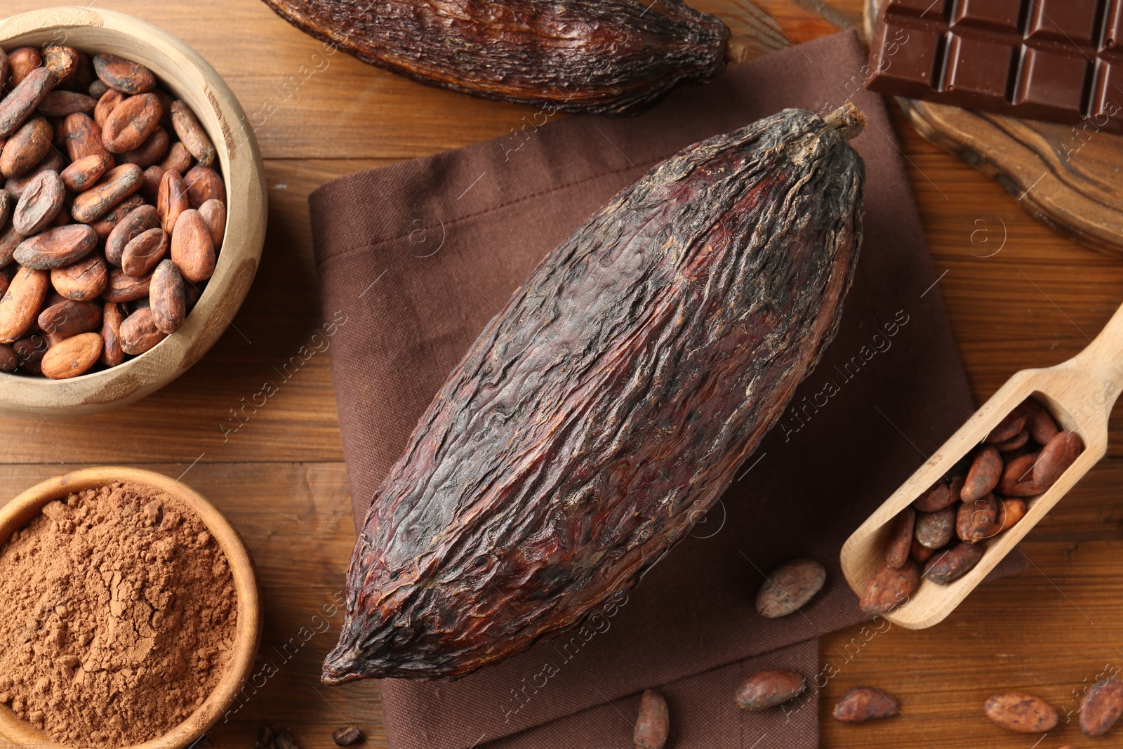 Photo of Cocoa pod, beans, powder and chocolate on wooden table, closeup