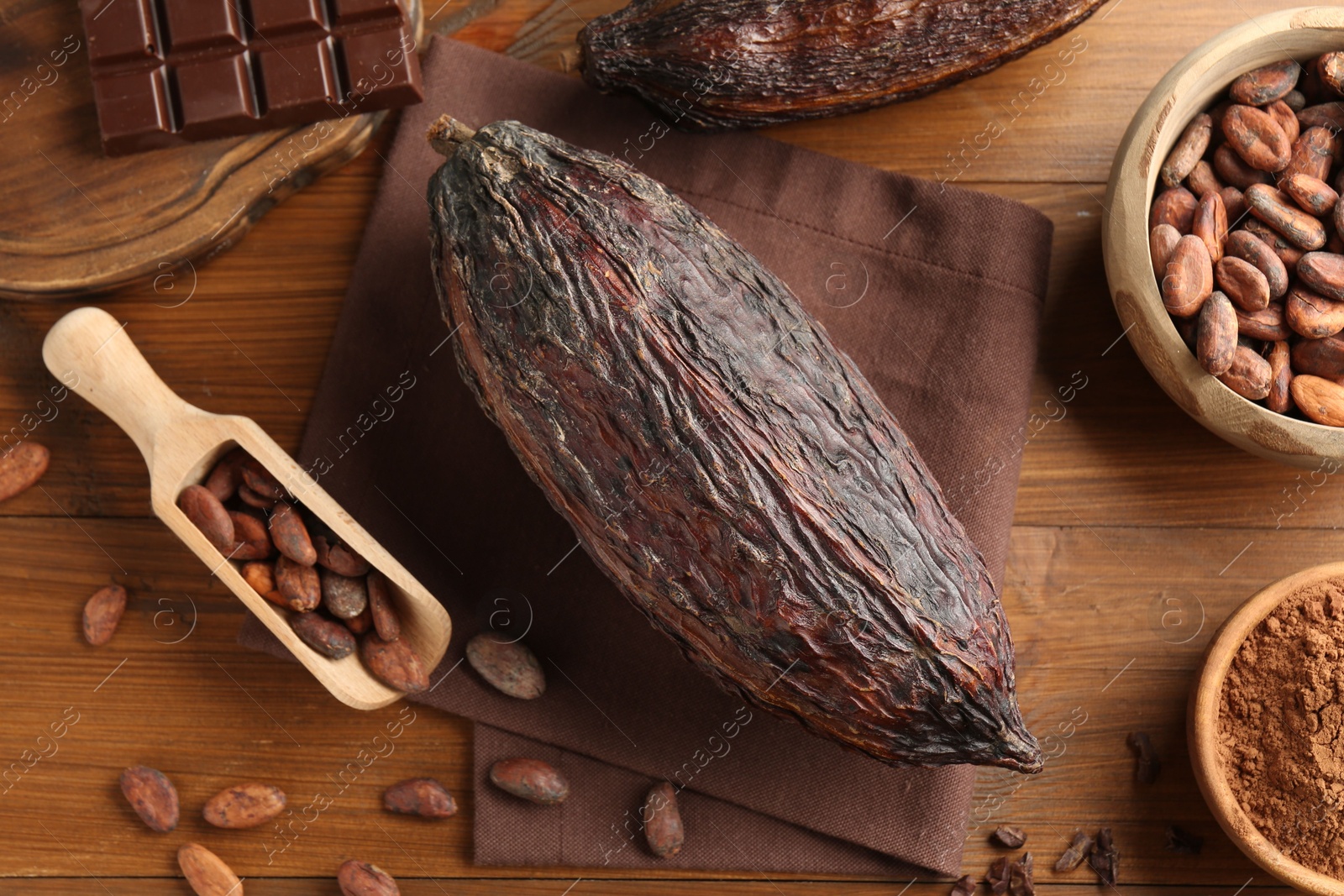 Photo of Cocoa pods, beans, powder and chocolate on wooden table, closeup