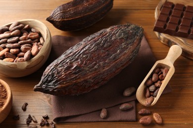 Cocoa pods, beans, powder and chocolate on wooden table, closeup