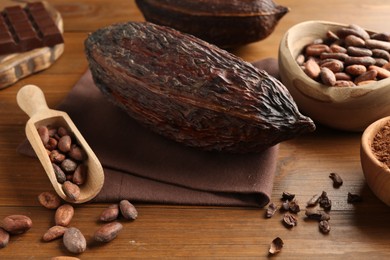 Photo of Cocoa pods, beans, powder and chocolate on wooden table, closeup