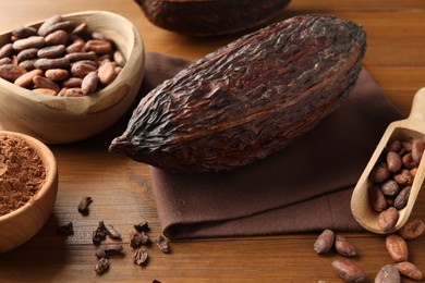 Cocoa pods, powder and beans on wooden table, closeup